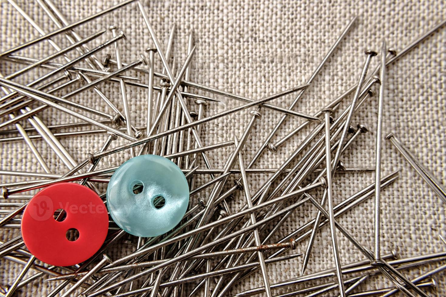 Red and blue button with seamstress pins on sack clothes. Close up. photo