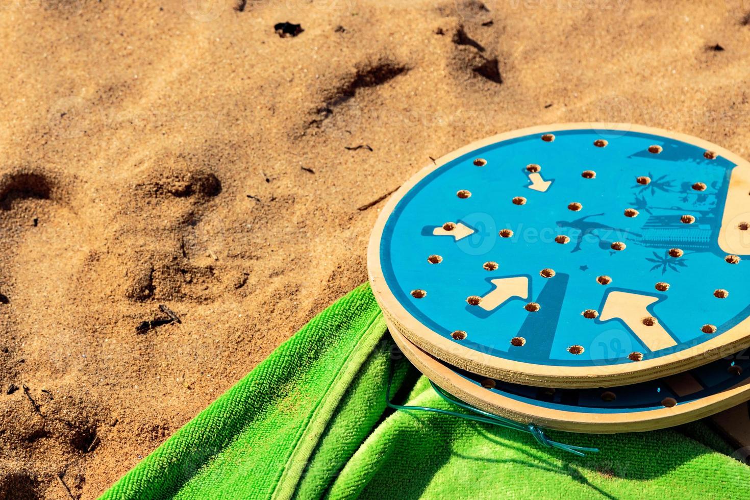 beach tennis rackets in the sand with a green towel. Horizontal image. photo