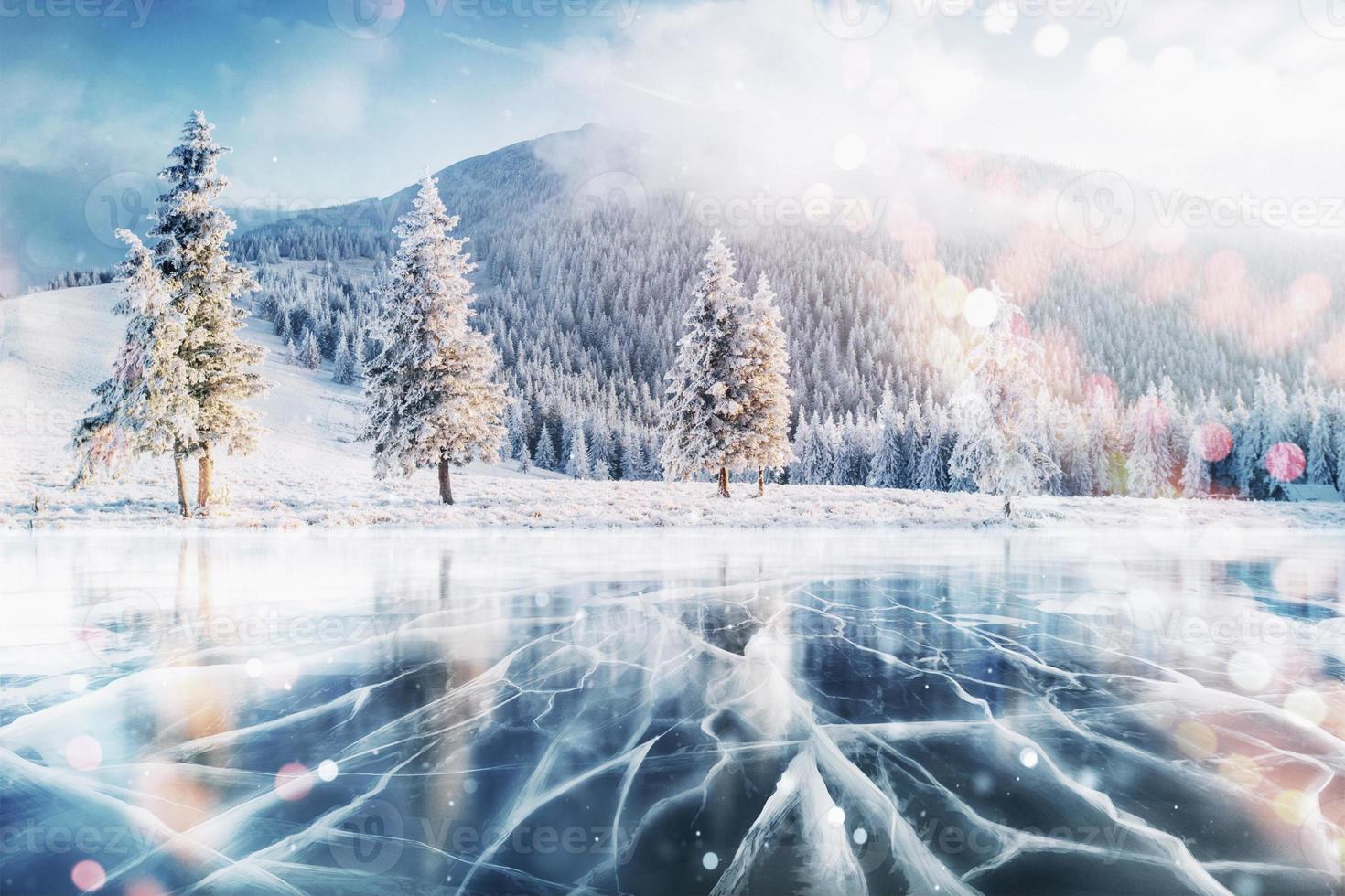 hielo azul y grietas en la superficie del hielo. lago congelado en las montañas de invierno. Está nevando. las colinas de pinos. invierno. cárpatos ucrania europa foto