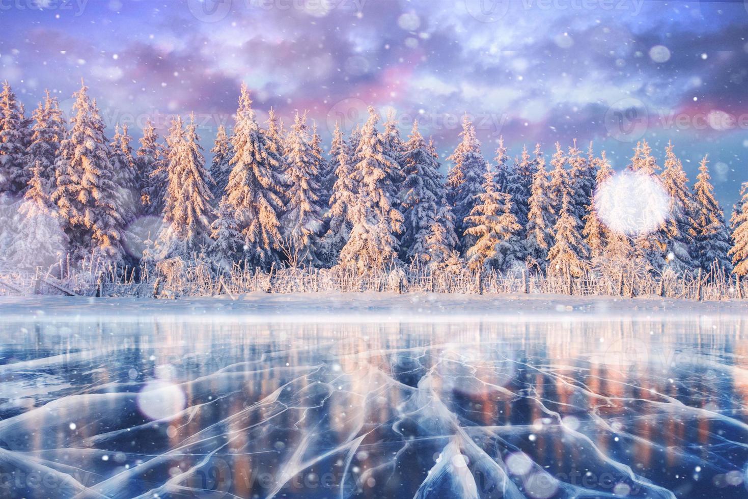 Blue ice and cracks on the surface of the ice. Frozen lake in winter mountains. It is snowing. The hills of pines. Winter. Carpathian Ukraine Europe photo