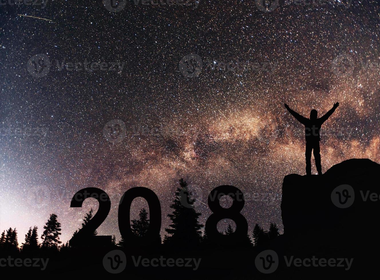 silueta joven feliz por el fondo de año nuevo 2018 de la galaxia de la vía láctea en una estrella brillante tono de cielo oscuro foto