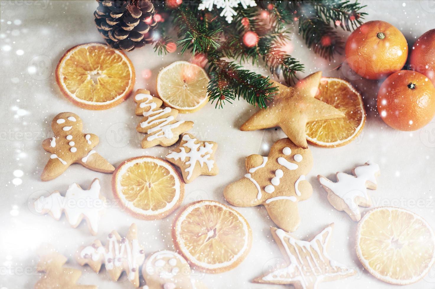 galletas de jengibre de navidad y naranja seca y especias en mesa blanca. sillas árboles de navidad, conos y adornos navideños foto