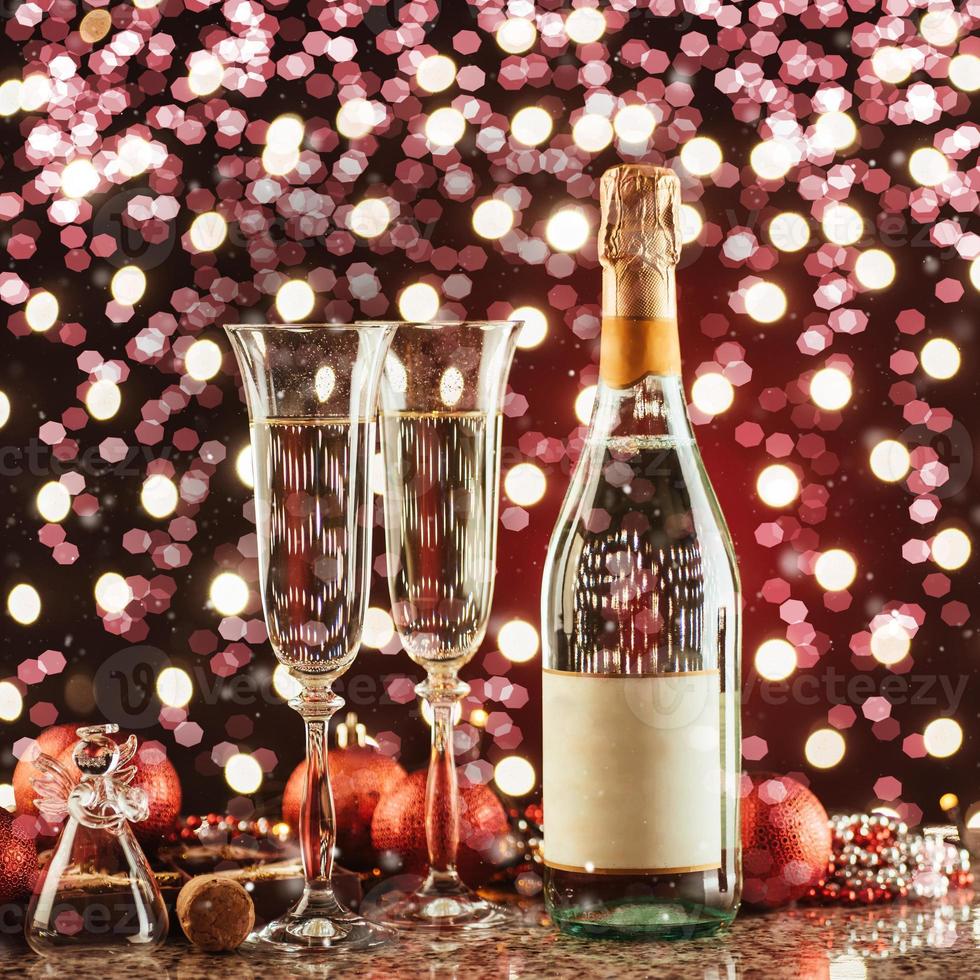 Christmas and New Year celebration with champagne. Pair of flute and bottle of Champagne for festive occasions against a dark background with gold shimmering light and bokeh photo