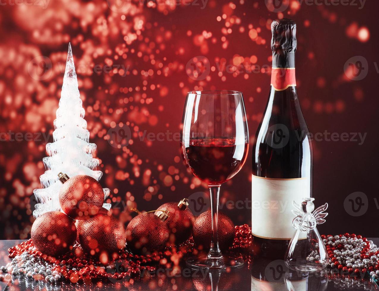 Christmas and New Year. Festive decorations, bottle of red wine and glass on the dark background. Happy New Year and Christmas. Bokeh light soft effect photo