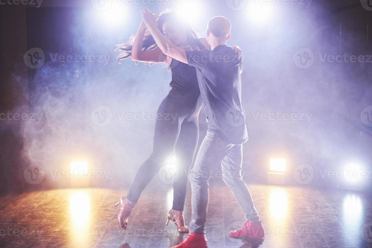 hábiles bailarines actuando en la habitación oscura bajo la luz y el humo del concierto. pareja sensual realizando una danza contemporánea artística y emocional foto