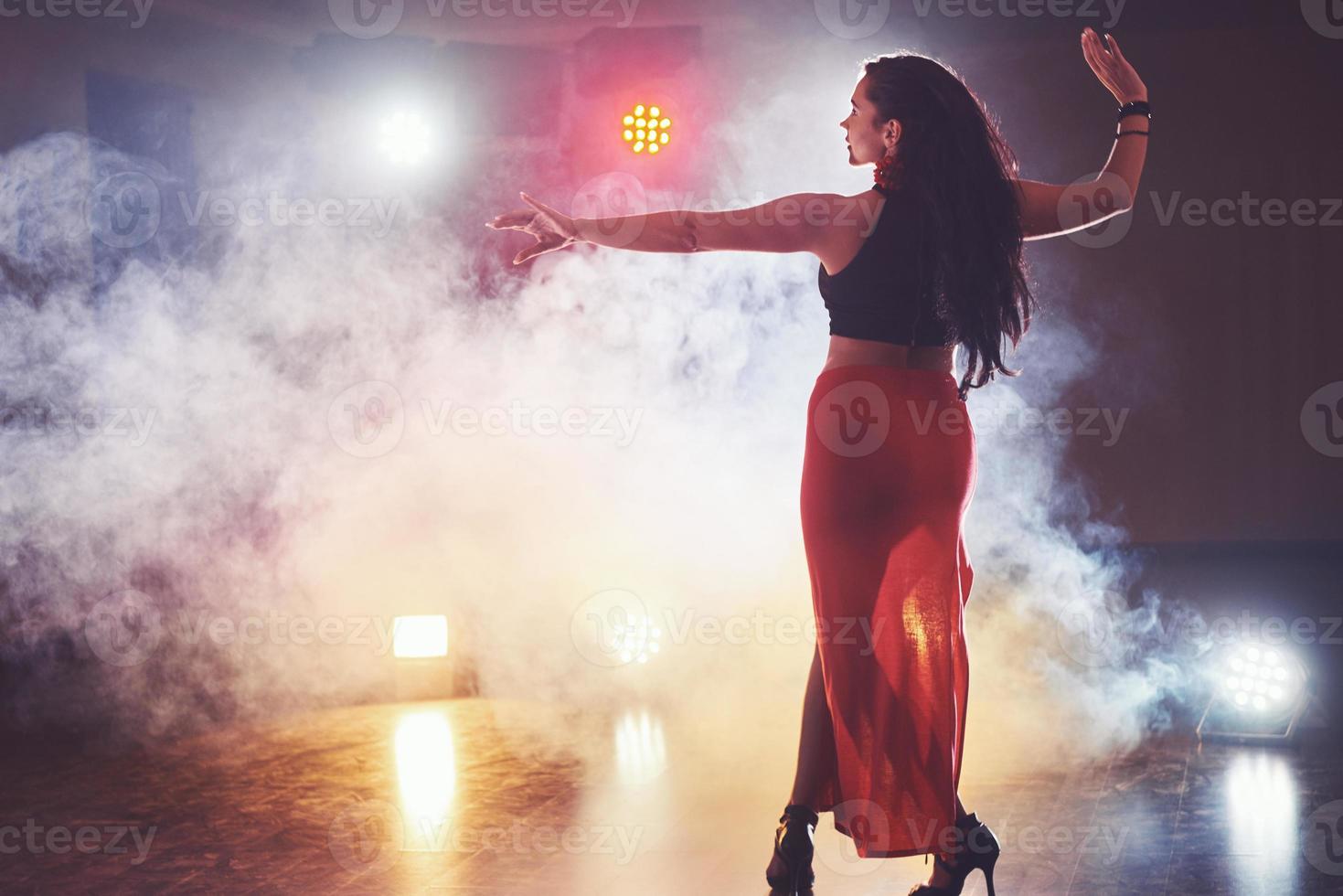 bailarina hábil y hermosa actuando en la habitación oscura bajo la luz y el humo del concierto, interpretando una danza contemporánea artística y emocional foto