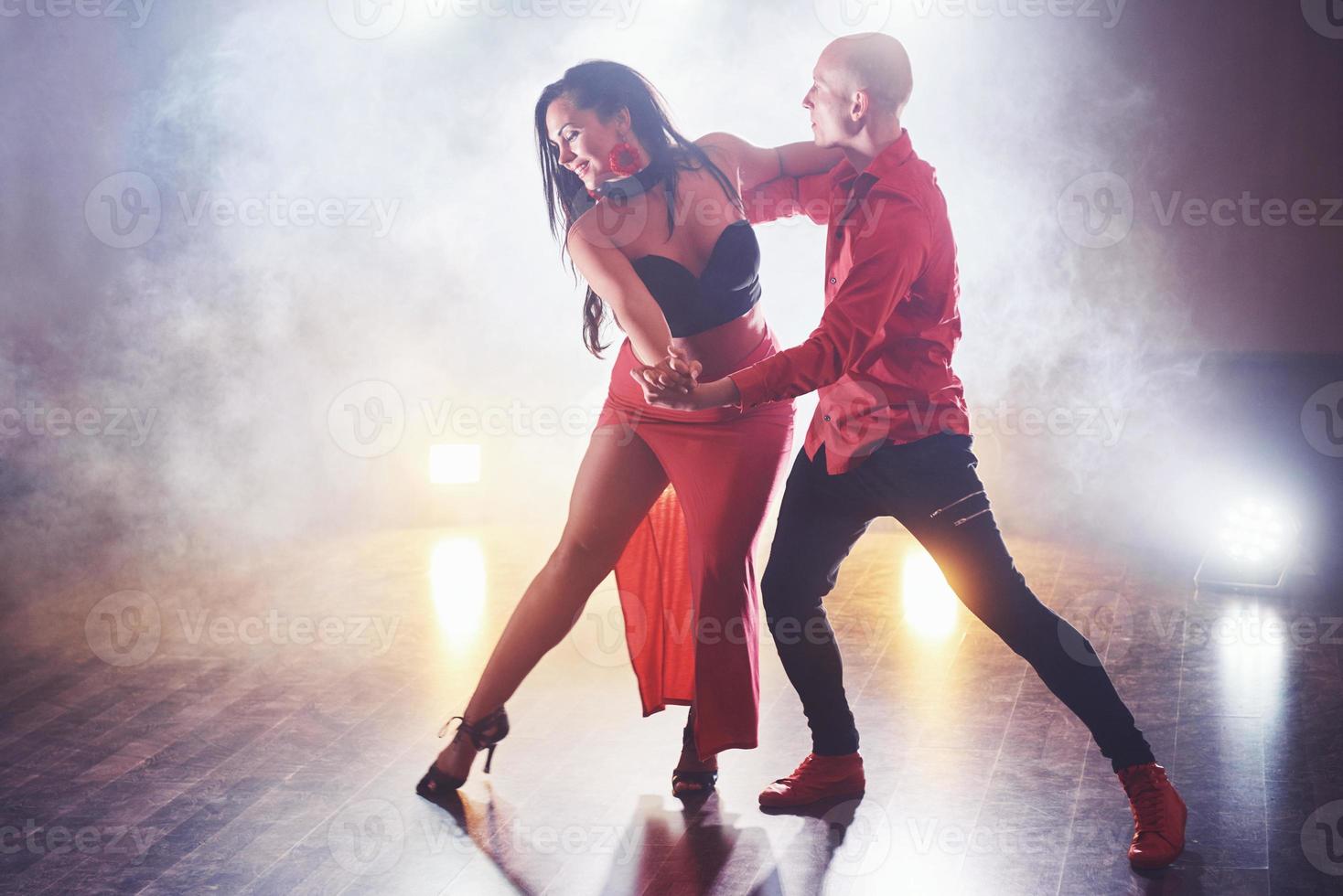 hábiles bailarines actuando en la habitación oscura bajo la luz y el humo del concierto. pareja sensual realizando una danza contemporánea artística y emocional foto