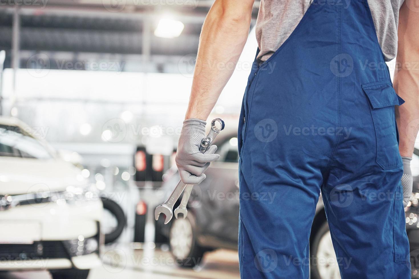 Hands of car mechanic with wrench in garage photo