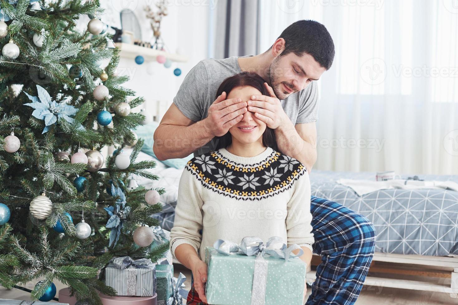 pareja joven celebrando la Navidad. un hombre de repente le presentó un regalo a su esposa. el concepto de felicidad y bienestar familiar foto