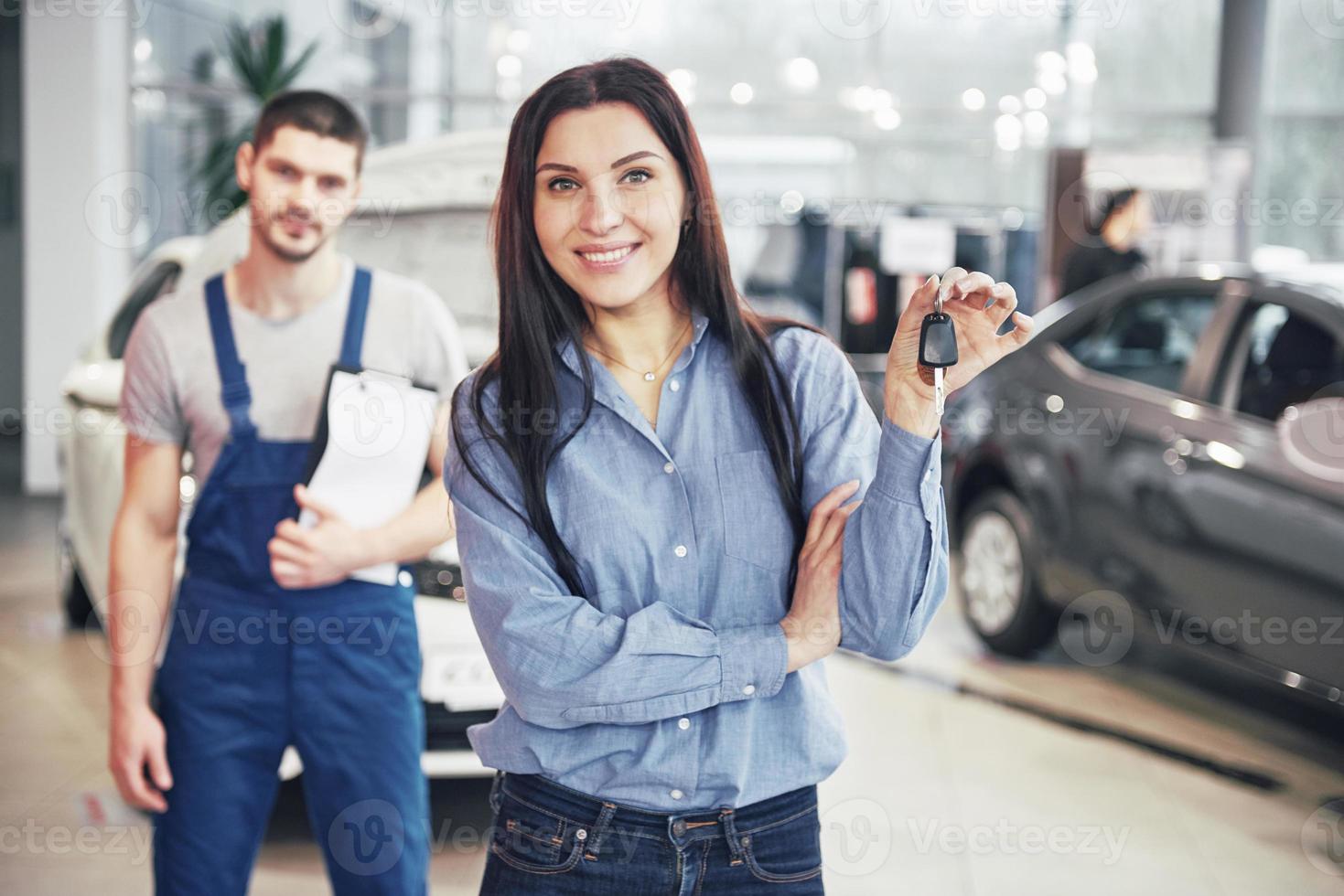 una mujer joven toma un automóvil del centro de servicio de automóviles. ella está feliz porque el trabajo está hecho a la perfección foto