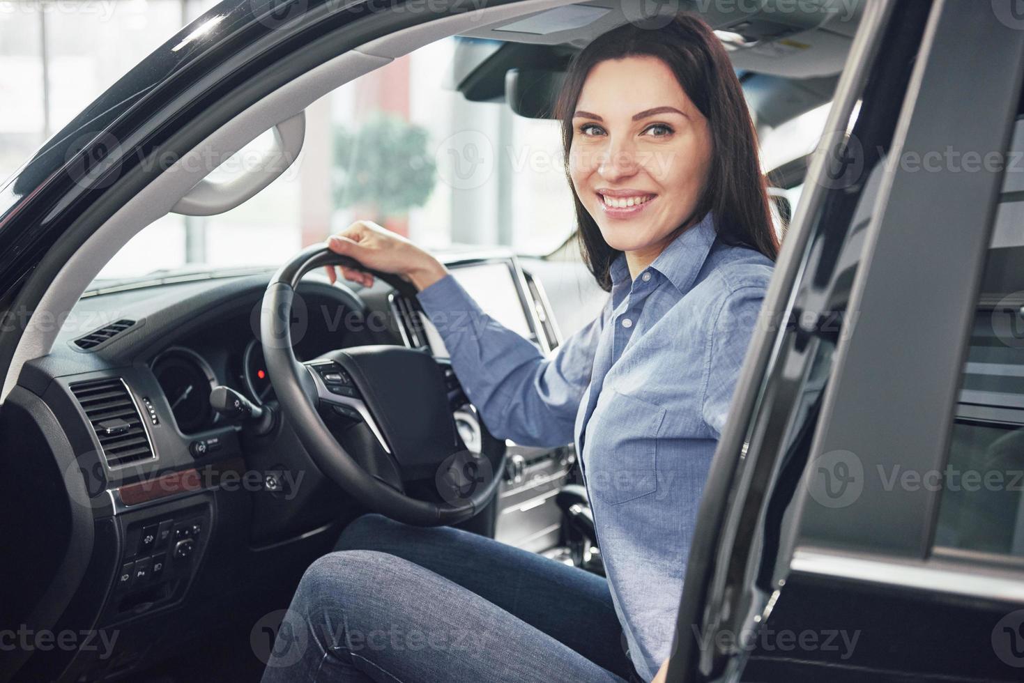auto business, car sale, consumerism and people concept - happy woman taking car key from dealer in auto show or salon photo