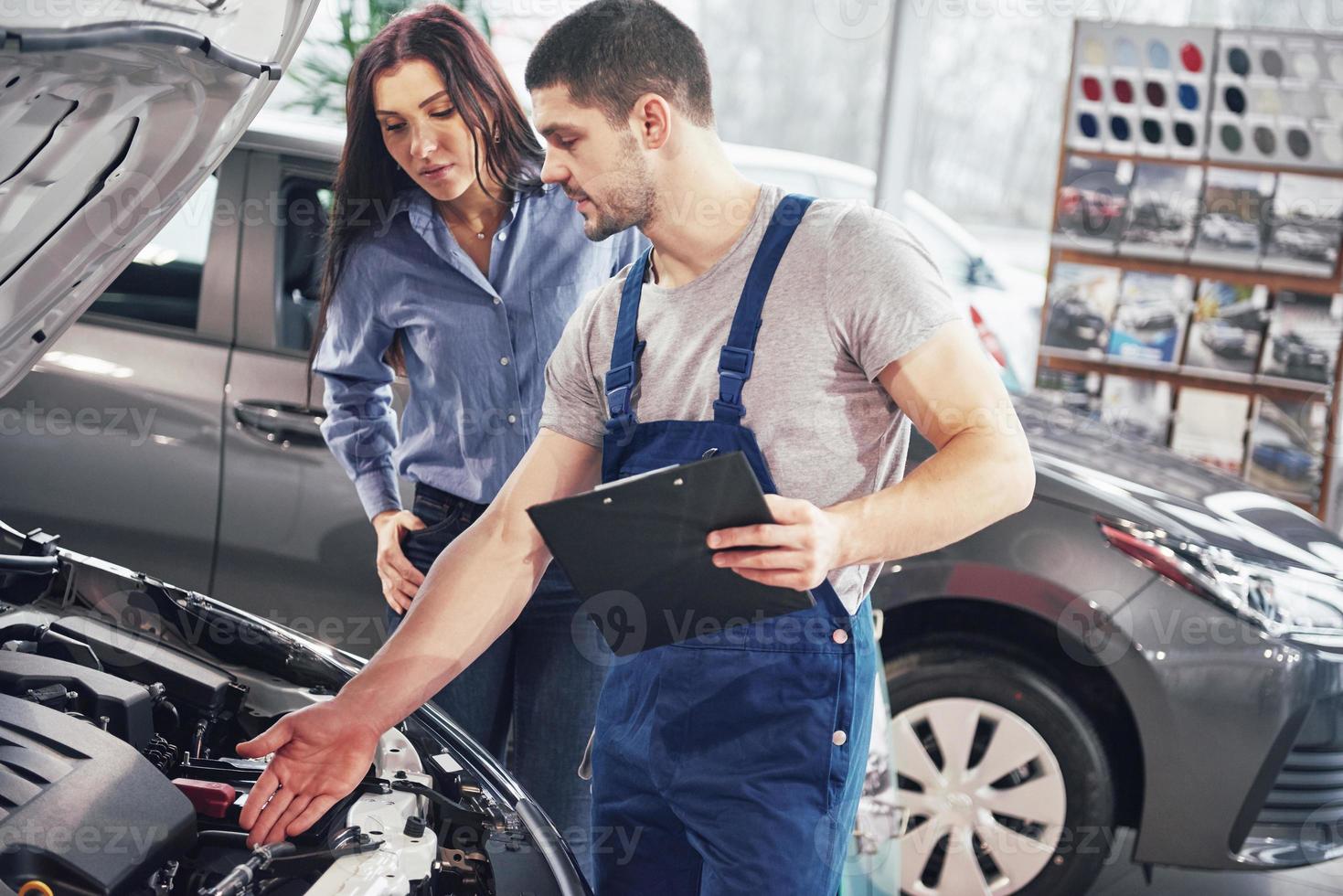 A man mechanic and woman customer discussing repairs done to her vehicle photo