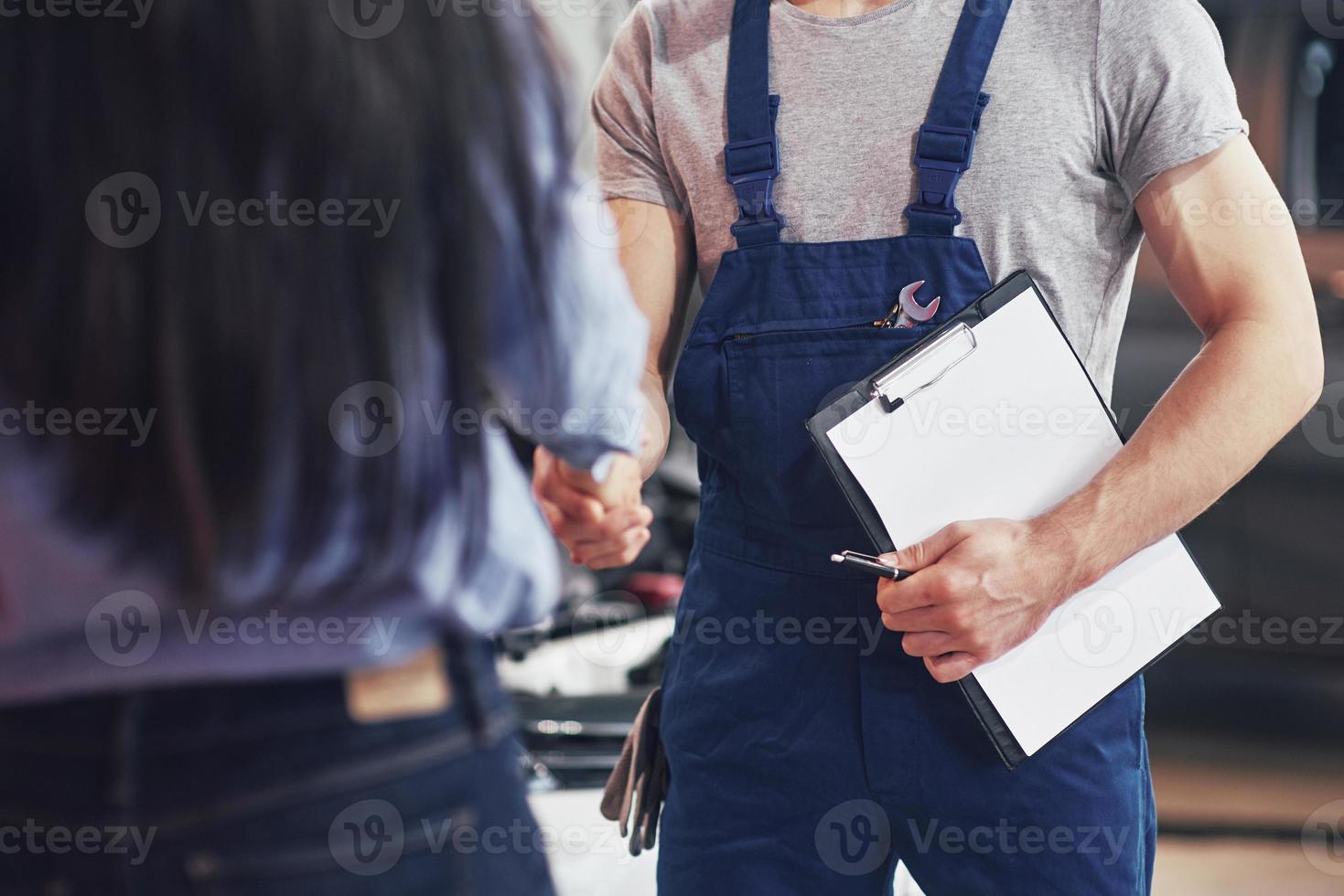 marido mecánico de automóviles y mujer cliente llegan a un acuerdo sobre la reparación del automóvil foto