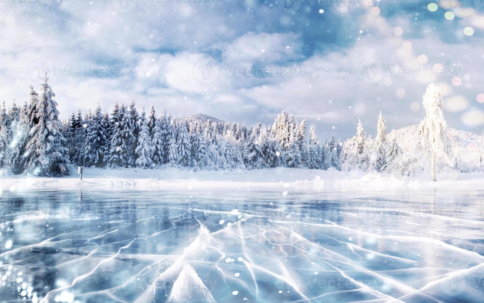 hielo azul y grietas en la superficie del hielo. lago congelado en las montañas de invierno. Está nevando. las colinas de pinos. invierno. cárpatos ucrania europa foto