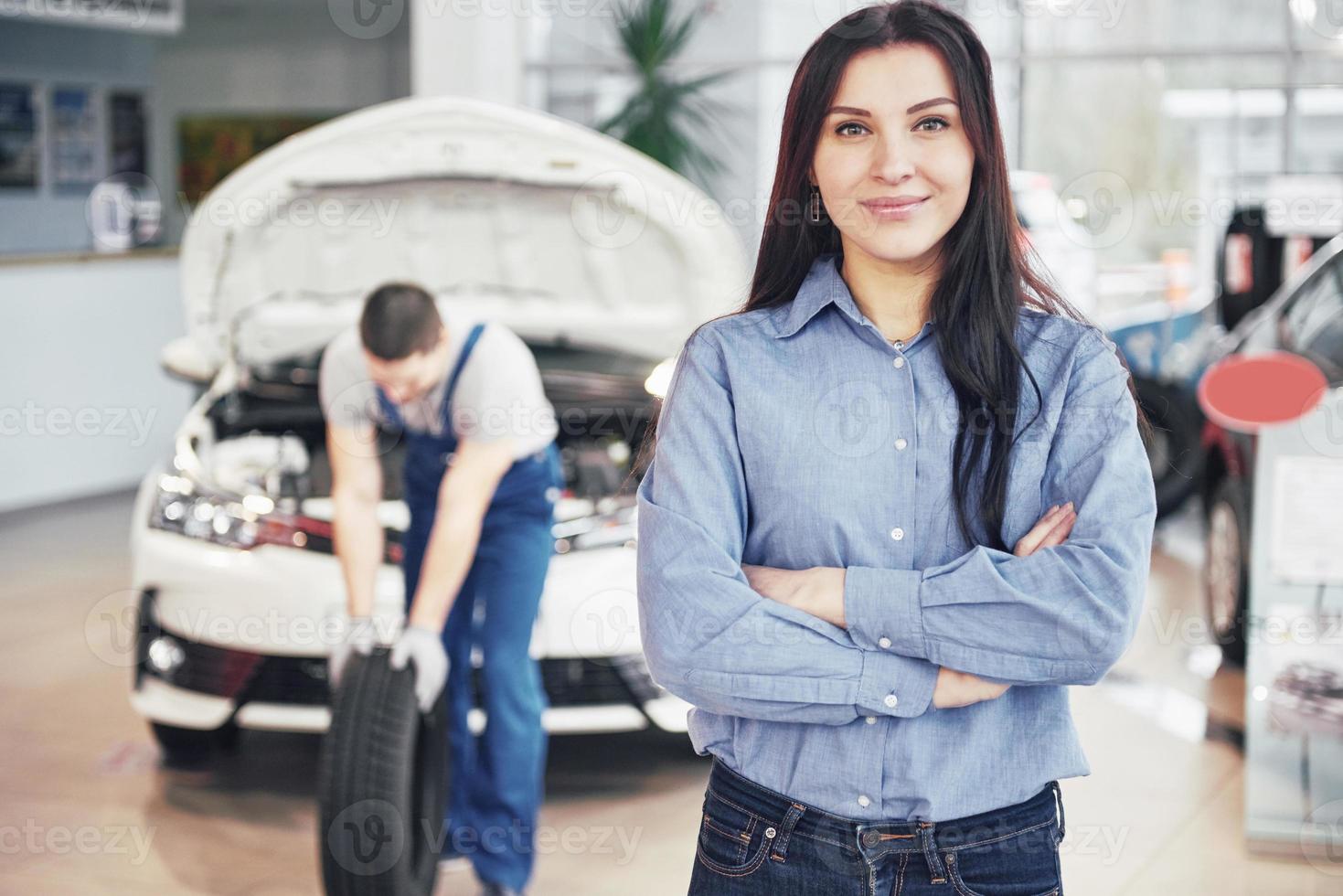 Mechanic holding a tire tire at the repair garage. The client woman waits for the job photo