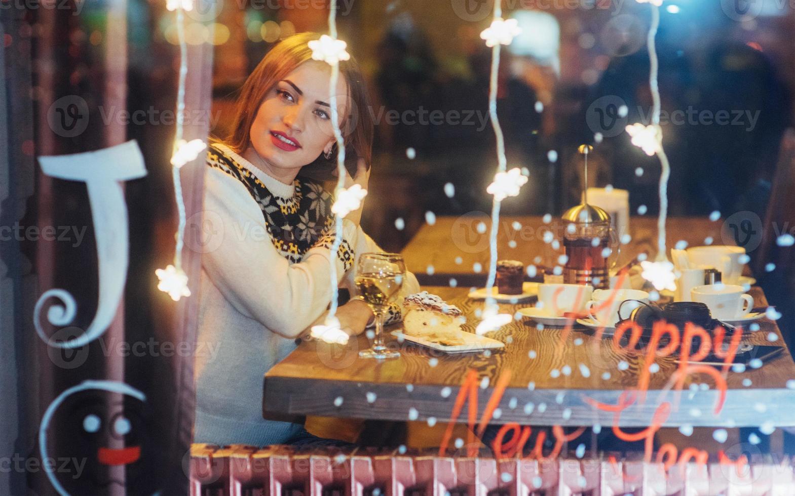 hermosa mujer joven sentada en el café, bebiendo vino. navidad, año nuevo, día de san valentín, concepto de vacaciones de invierno foto