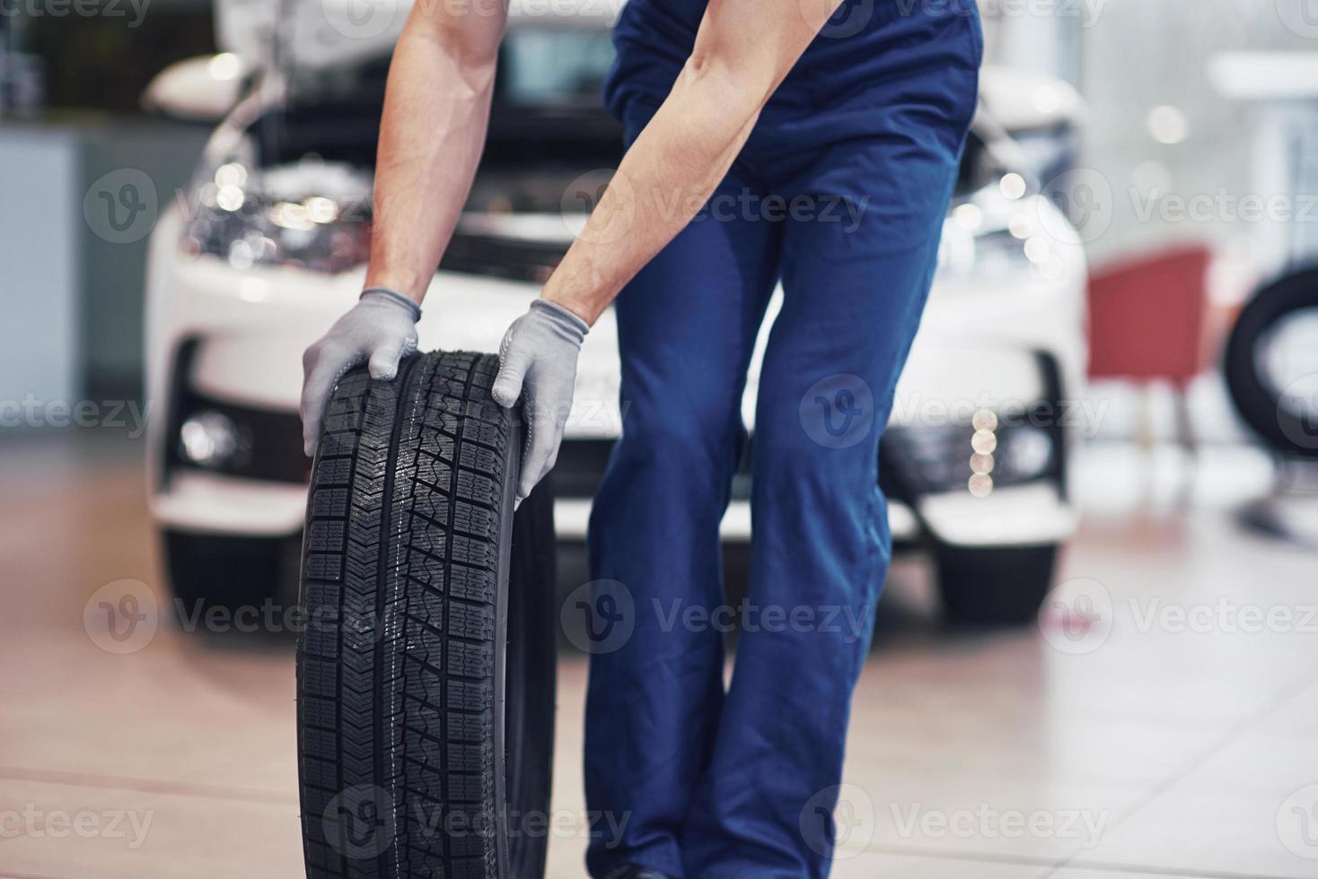 Mechanic holding a tire tire at the repair garage. replacement of winter and summer tires photo