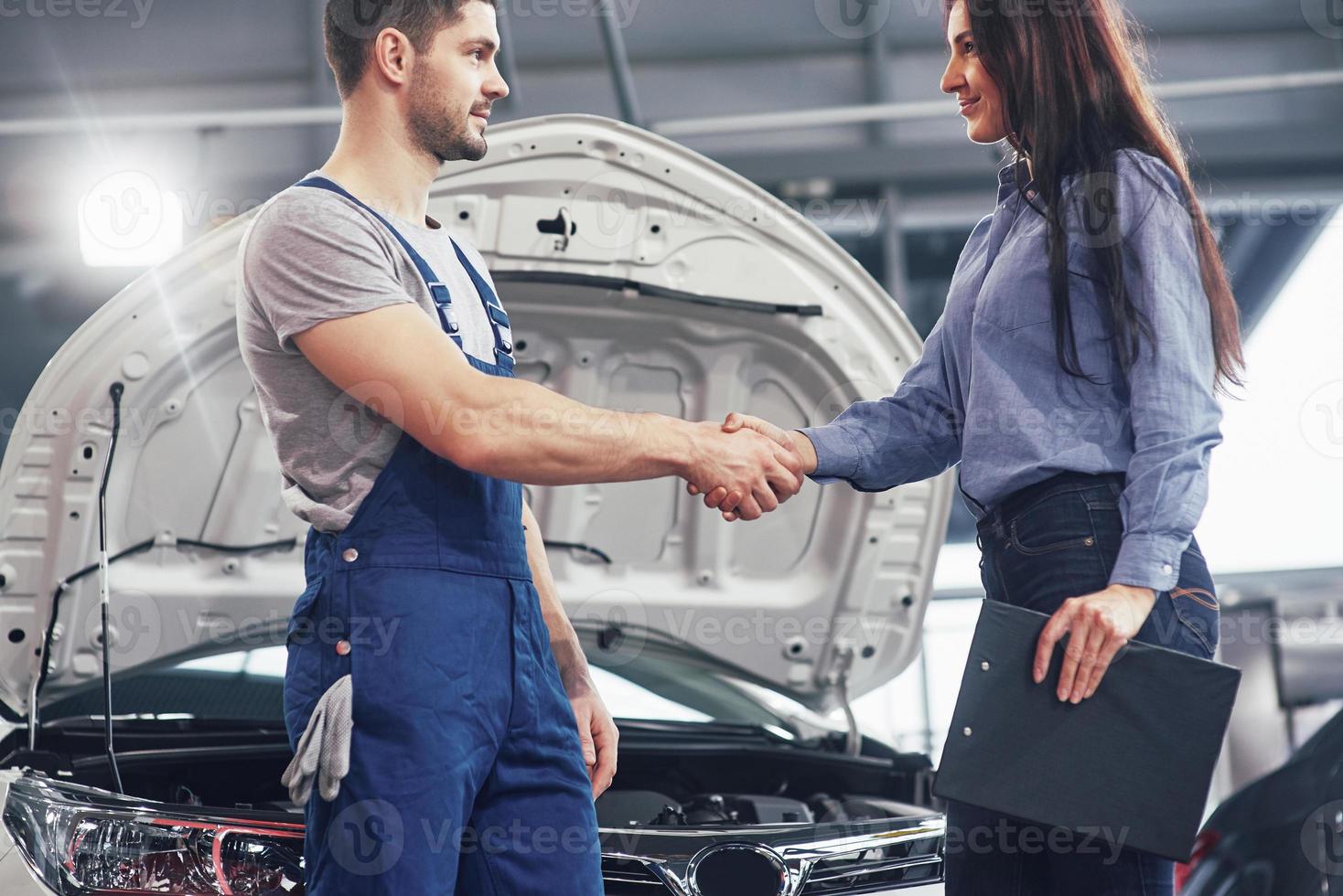 marido mecánico de automóviles y mujer cliente llegan a un acuerdo sobre la reparación del automóvil foto