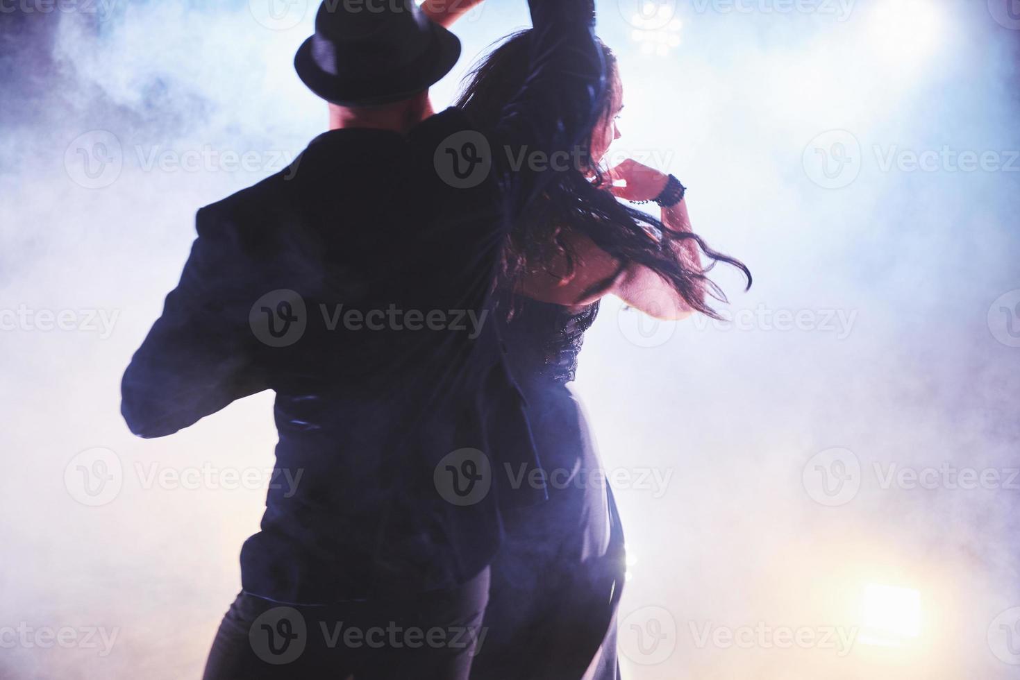 Skillful dancers performing in the dark room under the concert light and smoke. Sensual couple performing an artistic and emotional contemporary dance photo