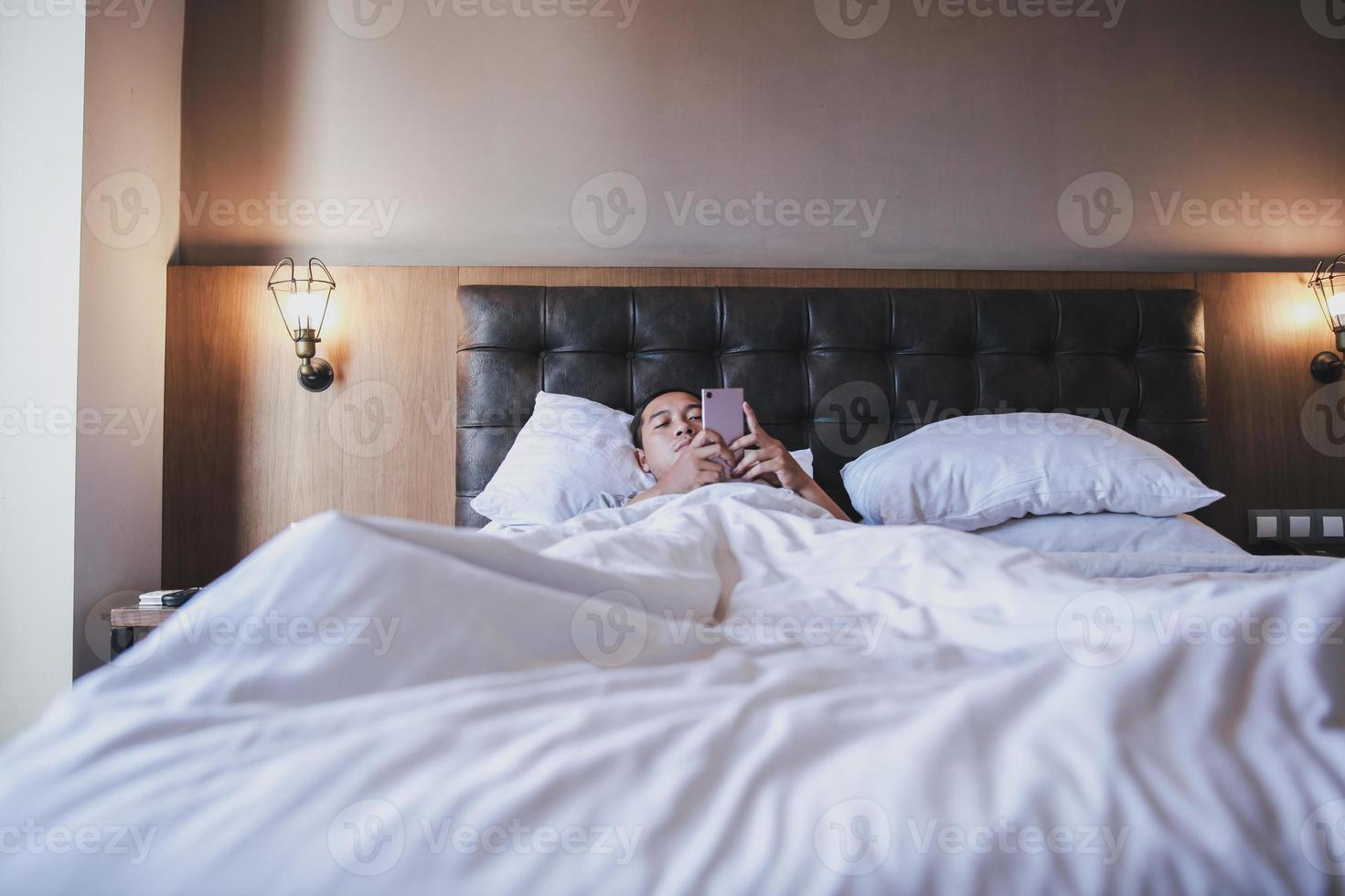 Insomnia men using smartphone  on the bed while lying under the blanket photo