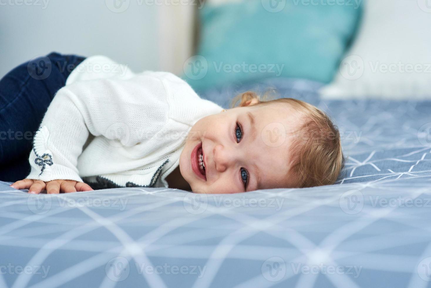 Friendly baby girl smile lying on the bed photo