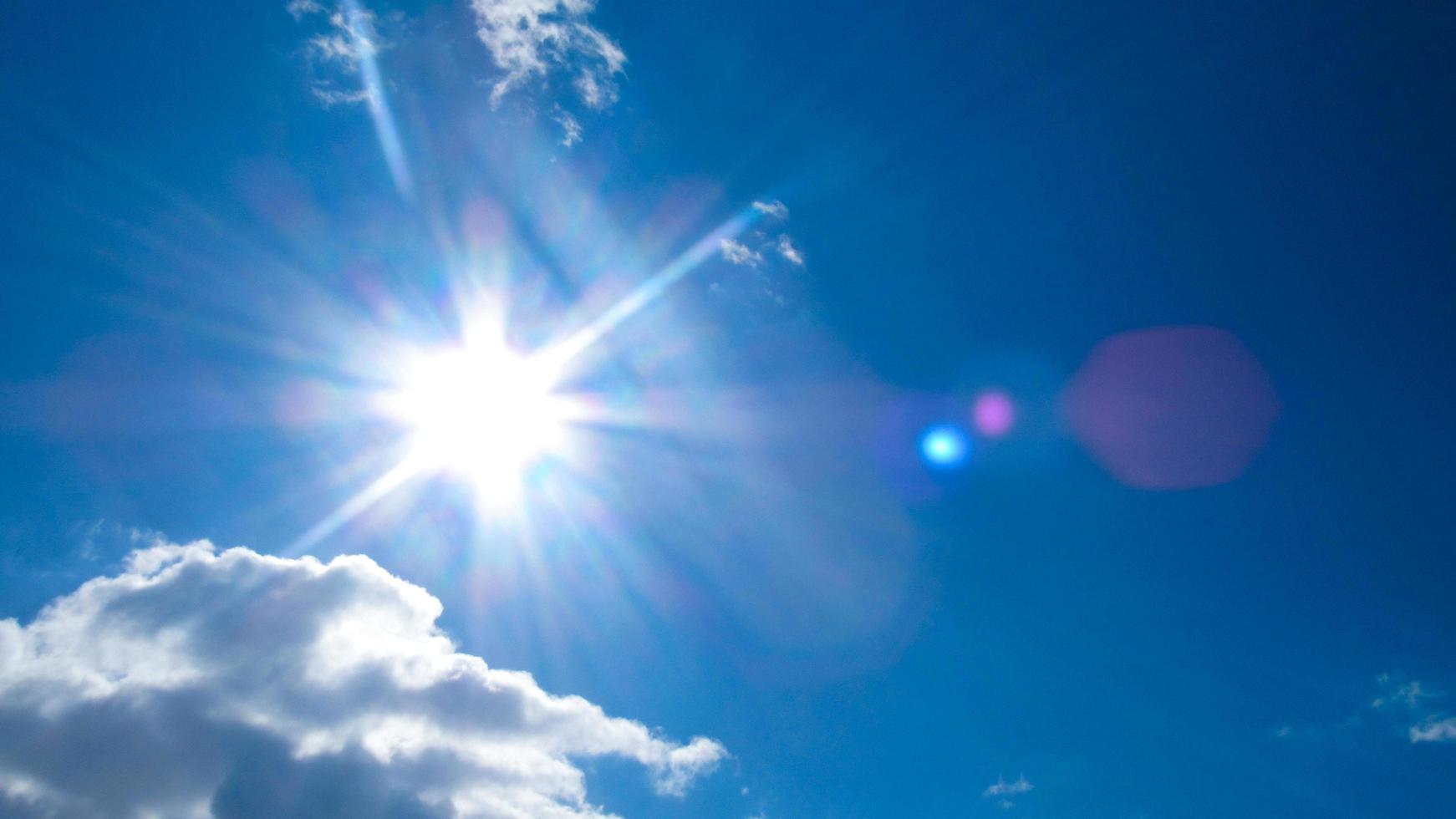 sun on the background of a blue sky with white clouds photo