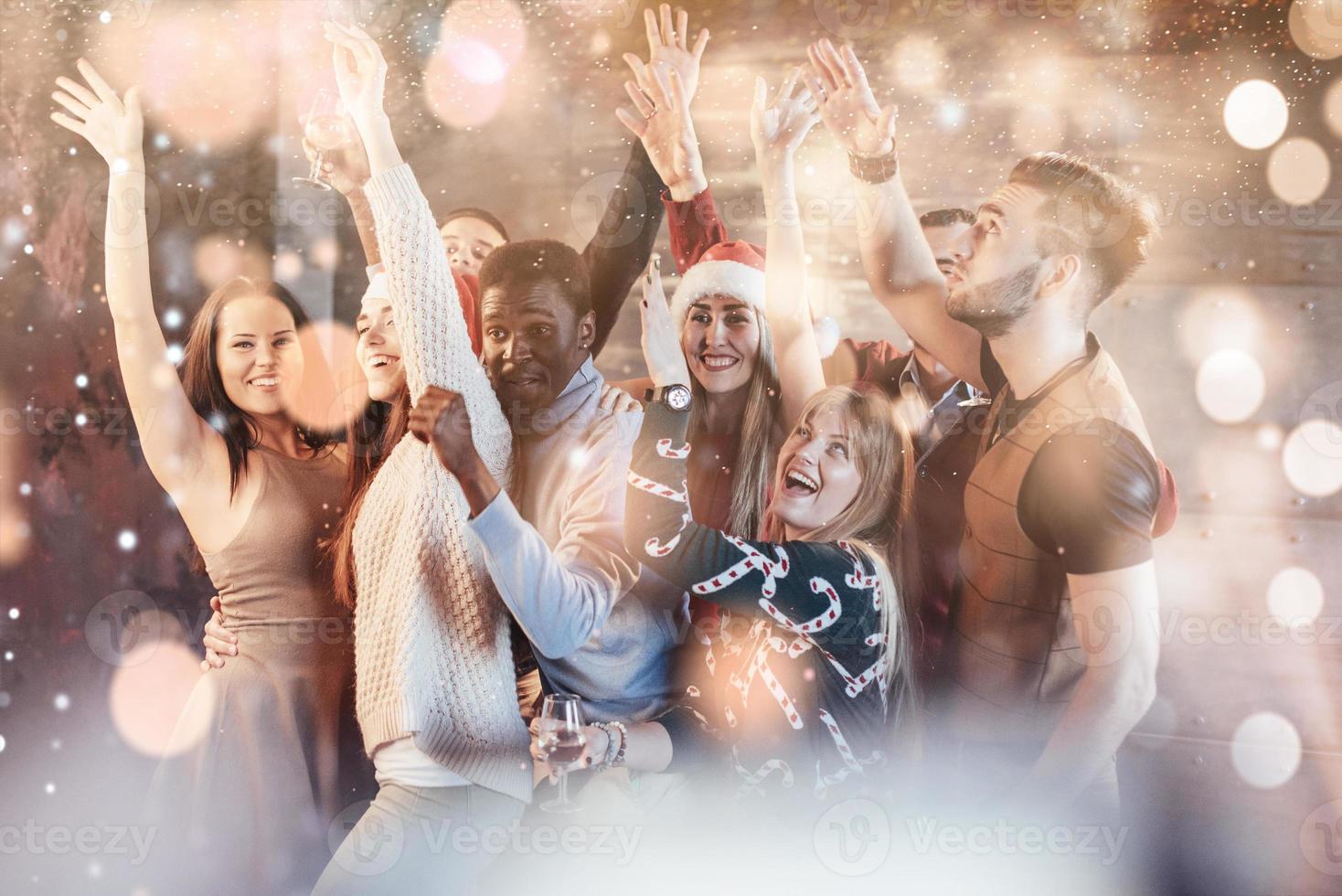 Party with friends. They love Christmas. Group of cheerful young people carrying sparklers and champagne flutes dancing in new year party and looking happy. Bokeh light soft effect photo