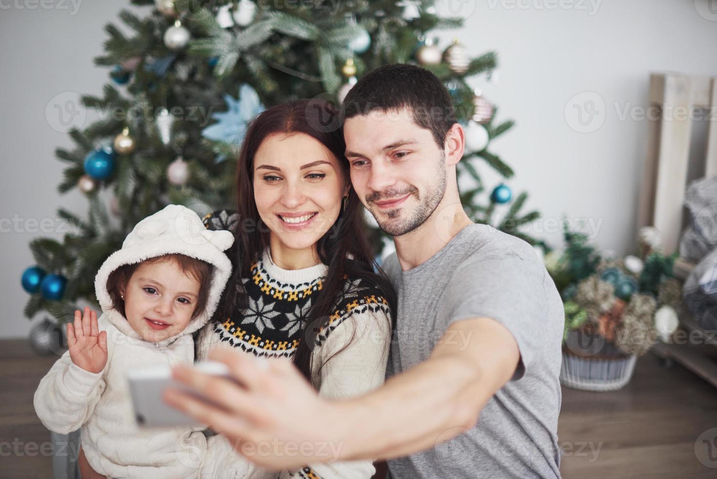Family gathered around a Christmas tree, using a tablet photo