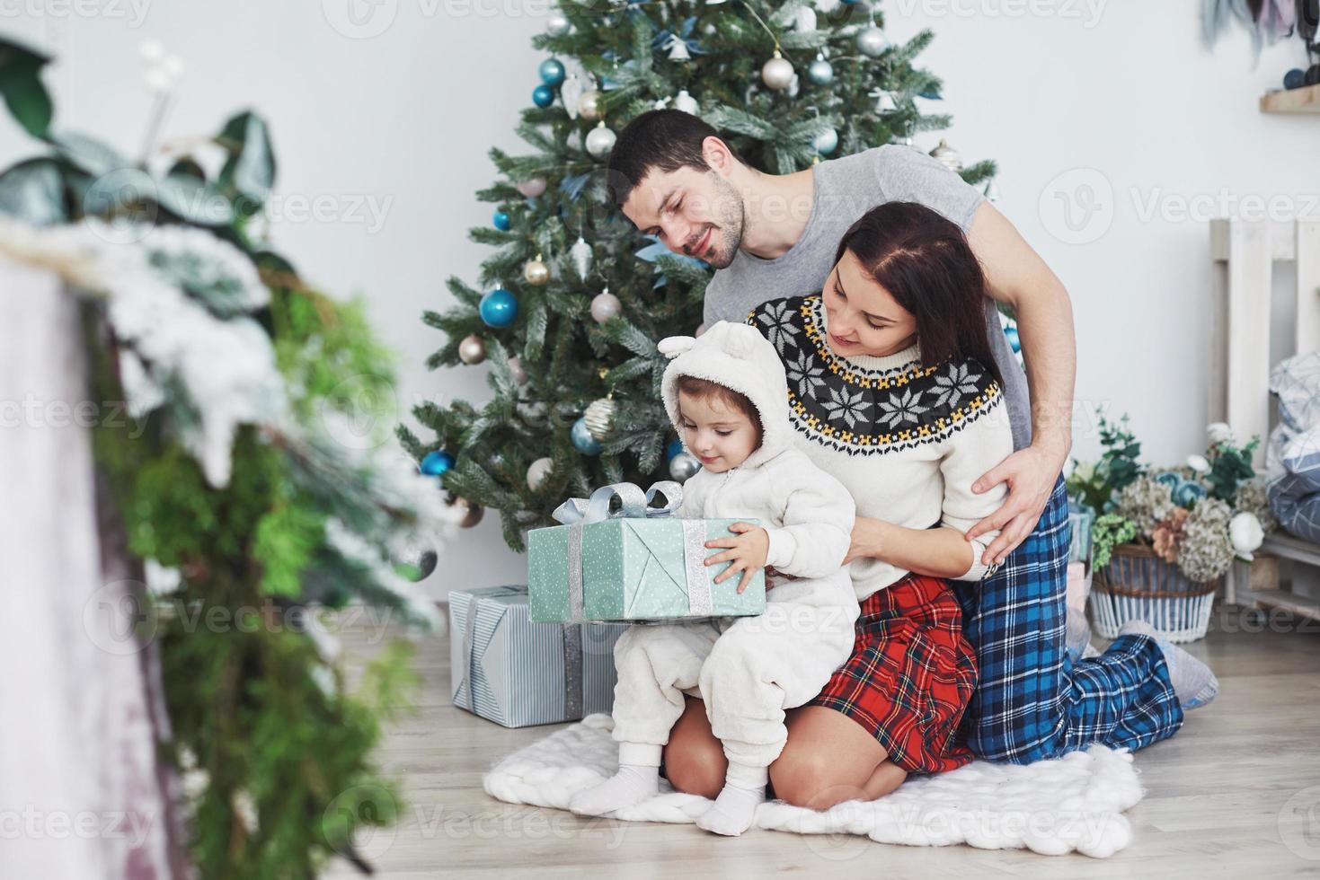 Happy family at christmas in morning opening gifts together near the fir tree. The concept of family happiness and well-being photo