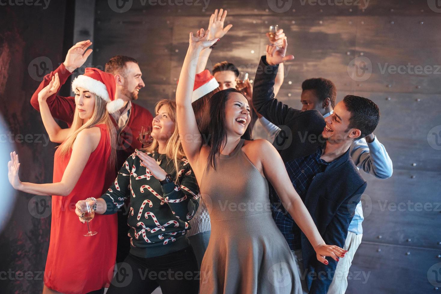 Party with friends. They love Christmas. Group of cheerful young people carrying sparklers and champagne flutes dancing in new year party and looking happy. Concepts about togetherness lifestyle photo