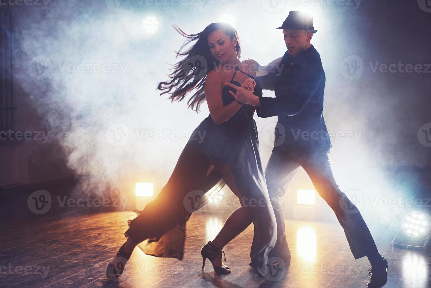 Skillful dancers performing in the dark room under the concert light and smoke. Sensual couple performing an artistic and emotional contemporary dance photo