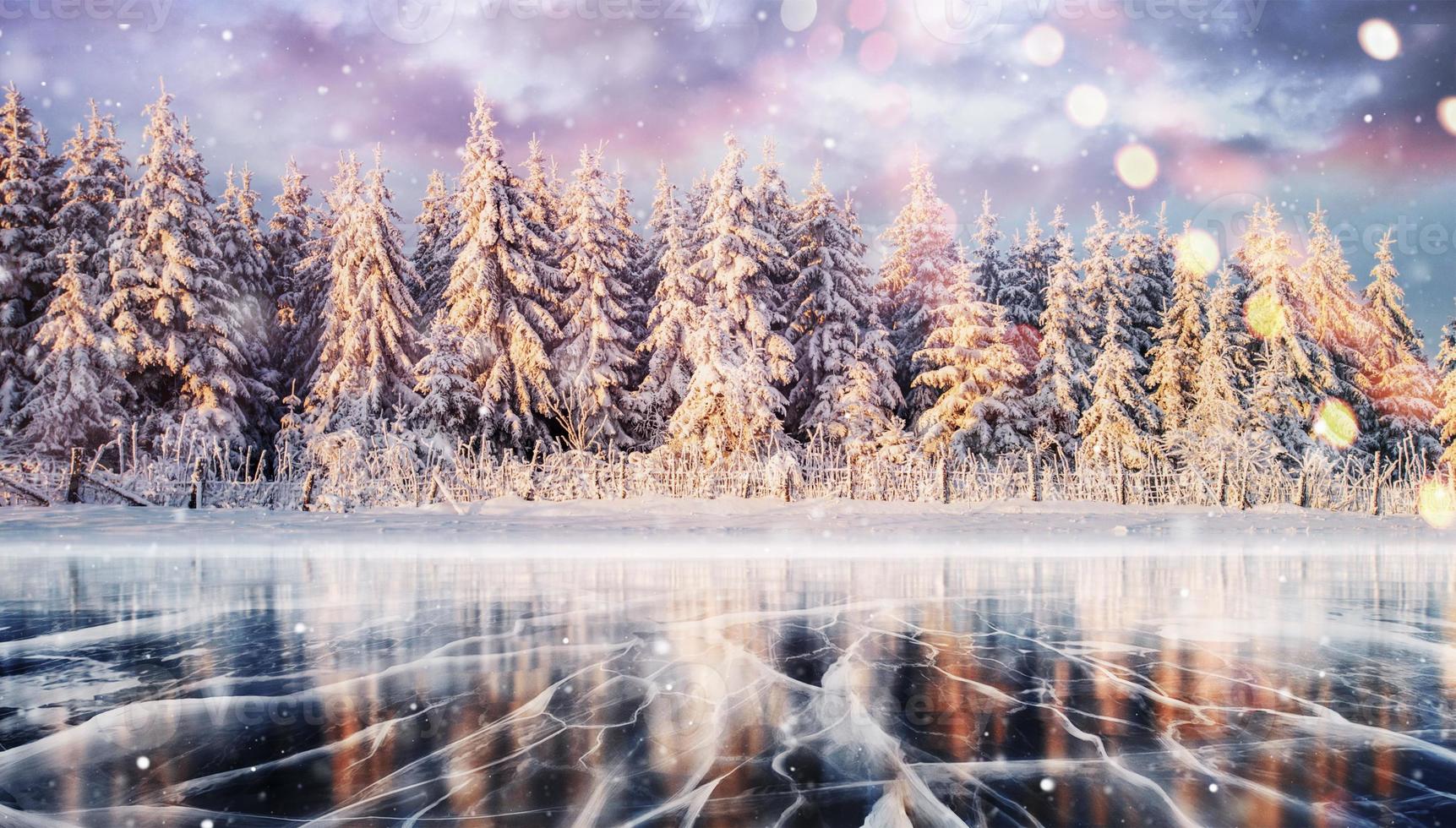 Blue ice and cracks on the surface of the ice. Frozen lake in winter mountains. It is snowing. The hills of pines. Winter. Carpathian Ukraine Europe photo