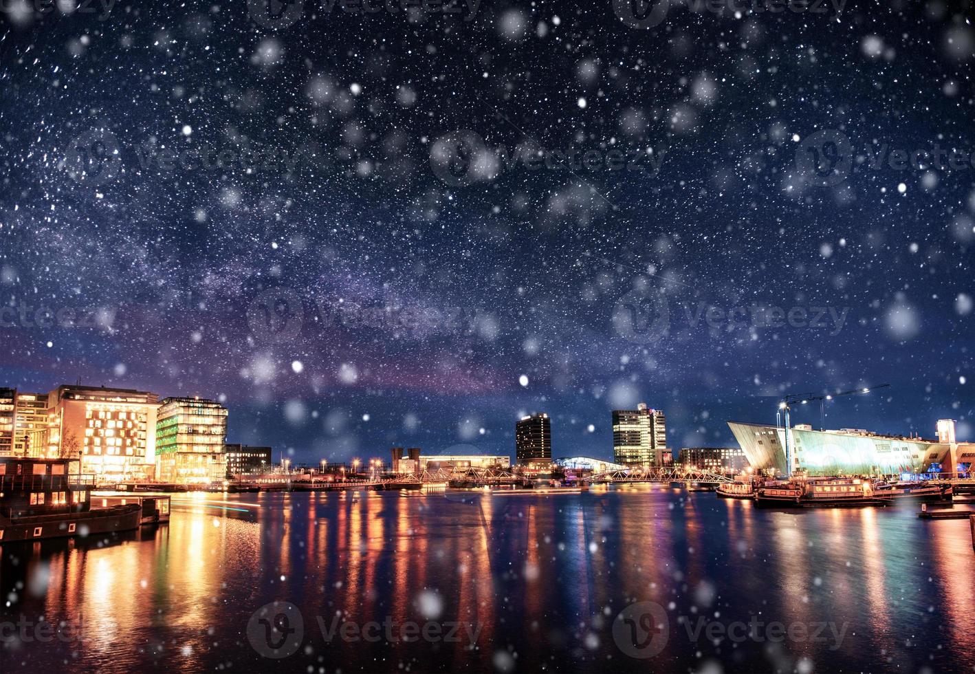 hermosa noche en amsterdam. iluminación nocturna de edificios y barcos cerca del agua en el canal durante una tormenta de nieve. efecto de luz bokeh, filtro suave foto