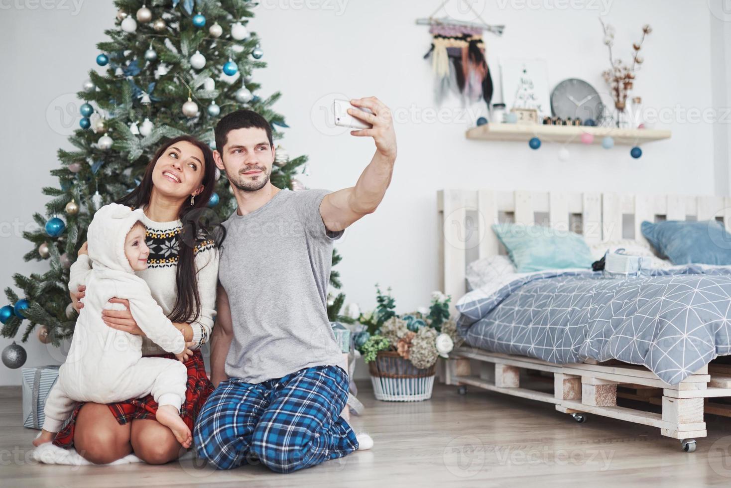 Family gathered around a Christmas tree, using a tablet photo