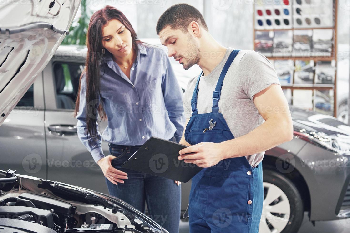 un hombre mecánico y una mujer cliente discutiendo las reparaciones hechas a su vehículo foto