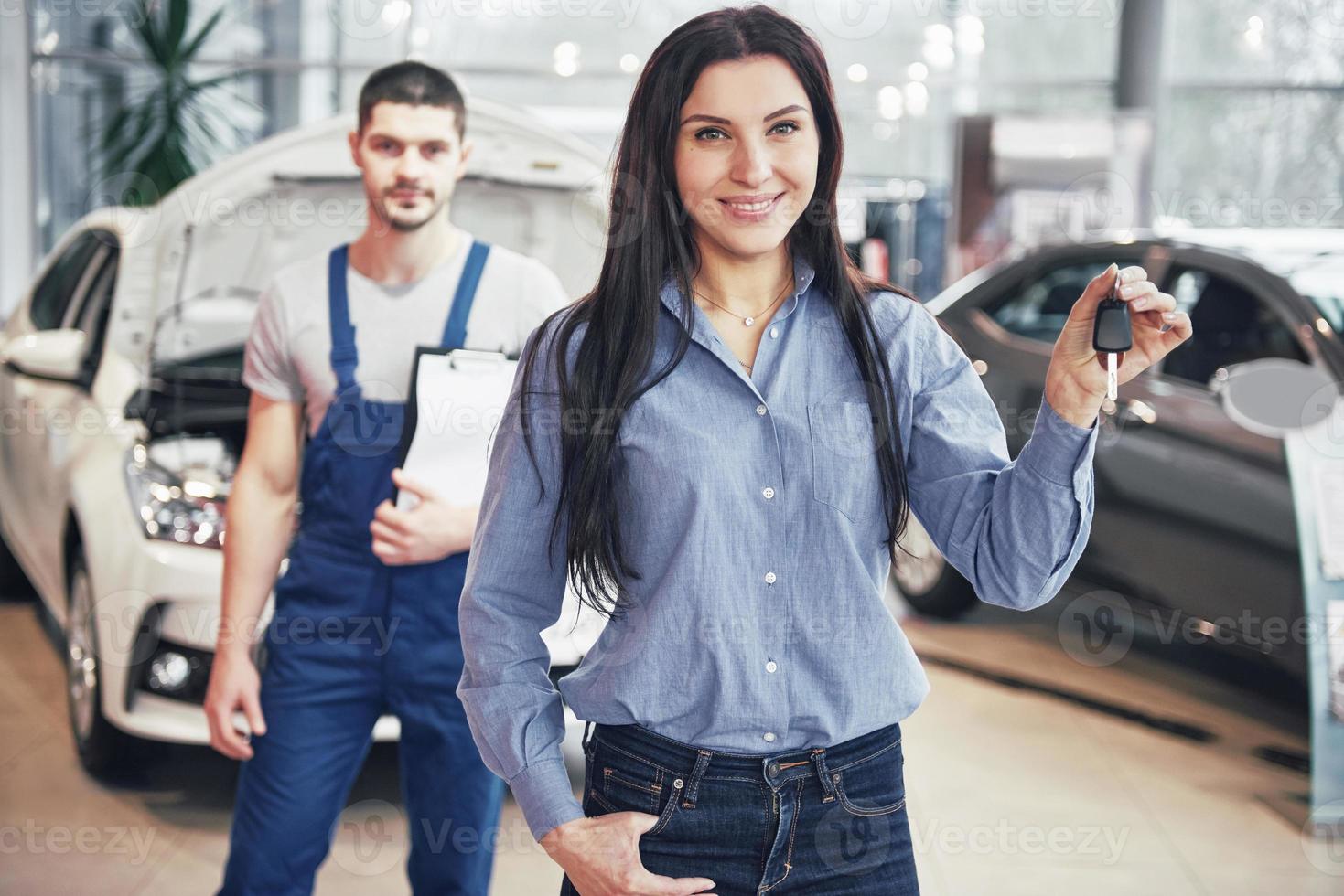 A young woman takes a car from the car service center. She is happy because the work is done perfectly photo