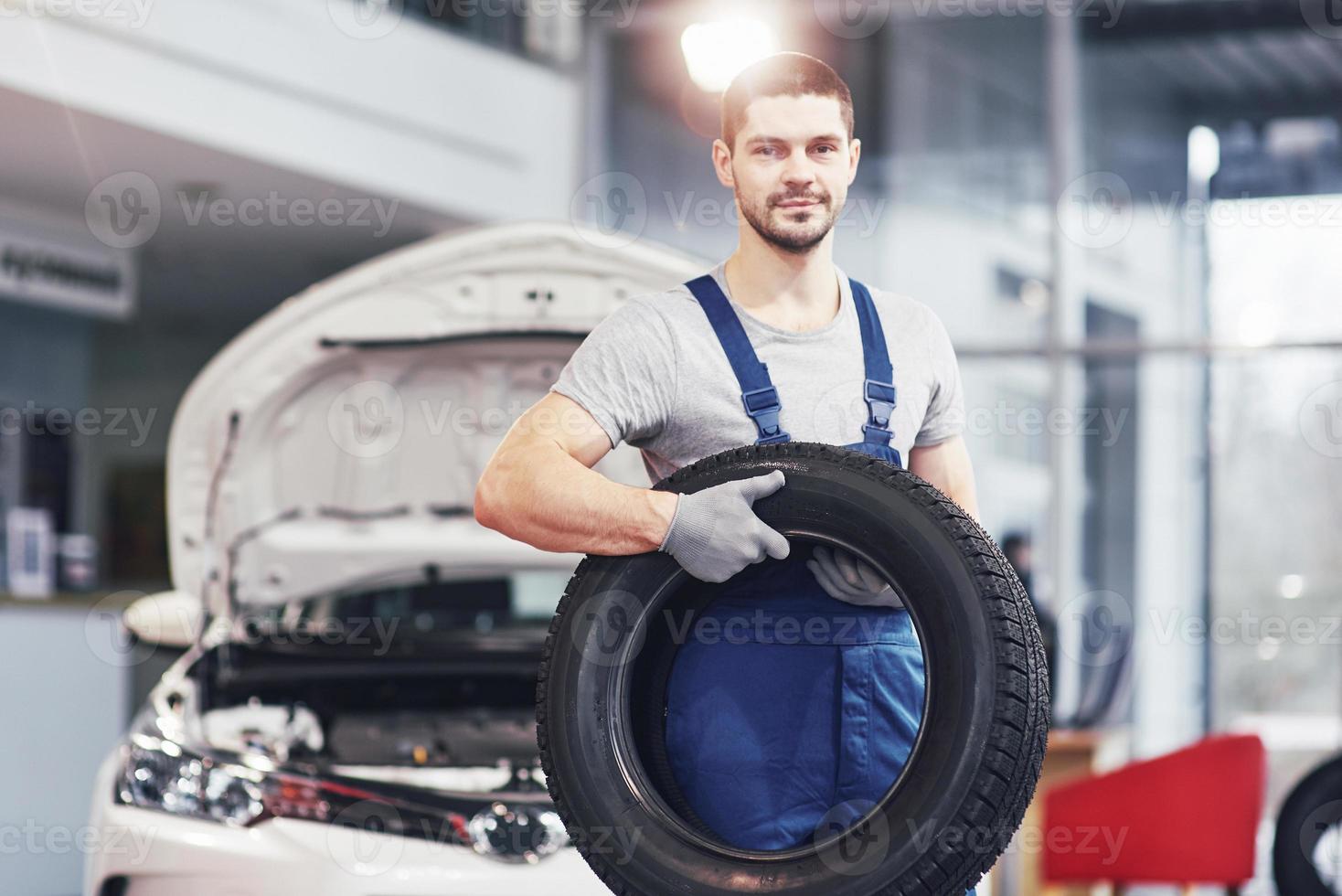 Mechanic holding a tire tire at the repair garage. replacement of winter and summer tires photo