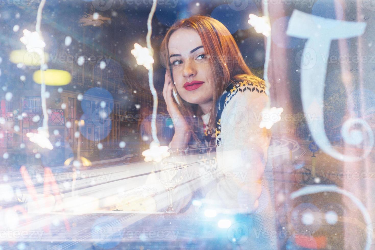 Young beautiful woman sitting in cafe, drinking coffee. Christmas, new year, winter holidays concept double exposure, night city photo