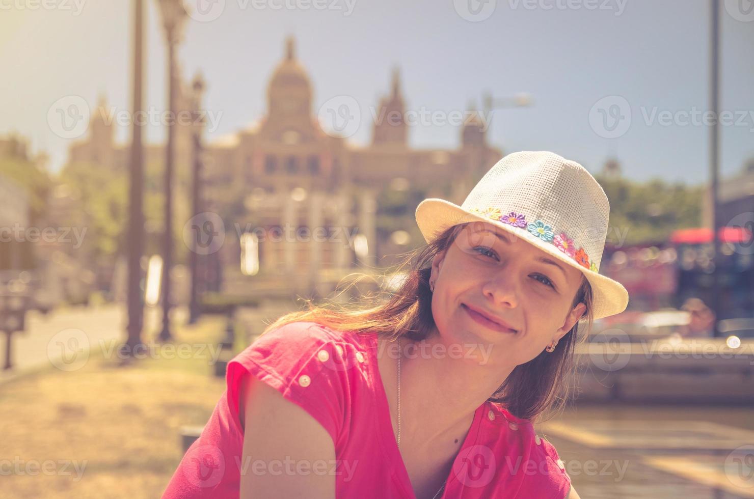 Young woman traveler with red dress and hat posing in Barcelona city in sunny summer day photo