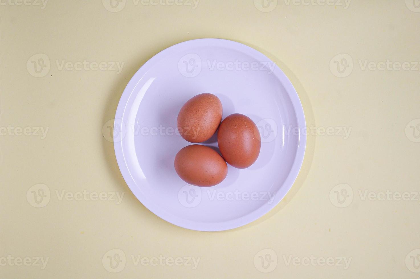 huevos marrones en plato blanco fondo amarillo suave. concepto de comida saludable, vista superior o fotografía flatlay foto