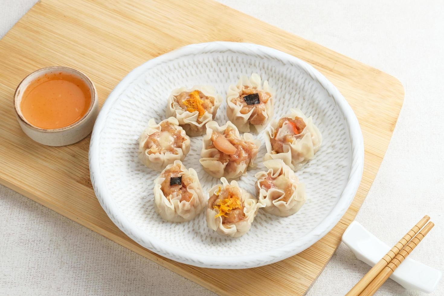 Mini Dim Sum chinese dumplings served on white plate, with sauce and chopstick. Close up. photo