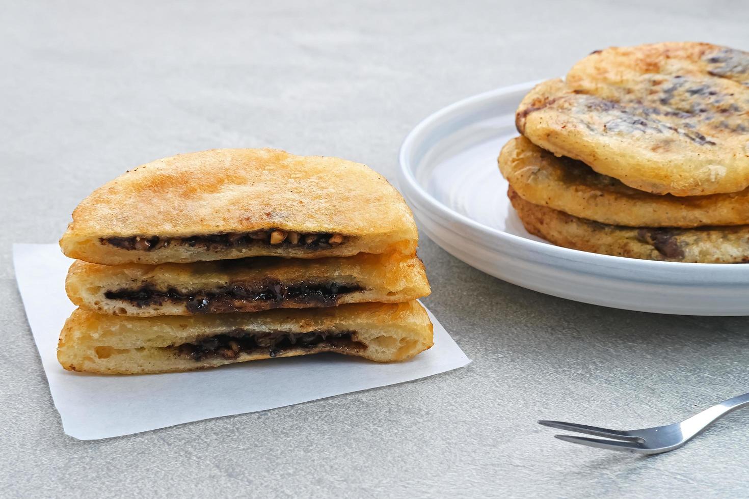 Hotteok, South Korean pancakes or fried dough with nuts and sugar filling, traditional street food. Selected focus. photo