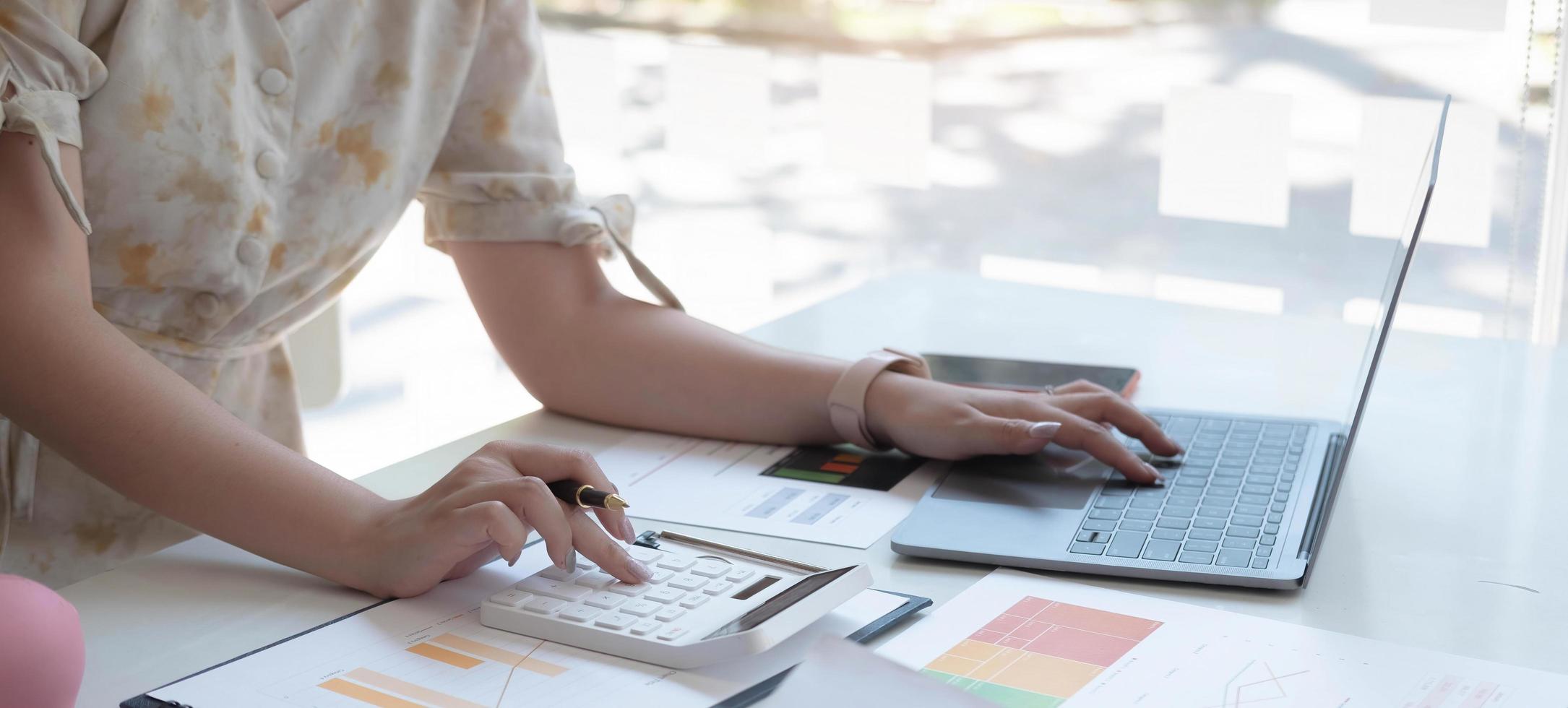 Close up woman hand using calculator and working with laptop calculate about finance accounting at coffeeshop outdor.finance accounting concept photo