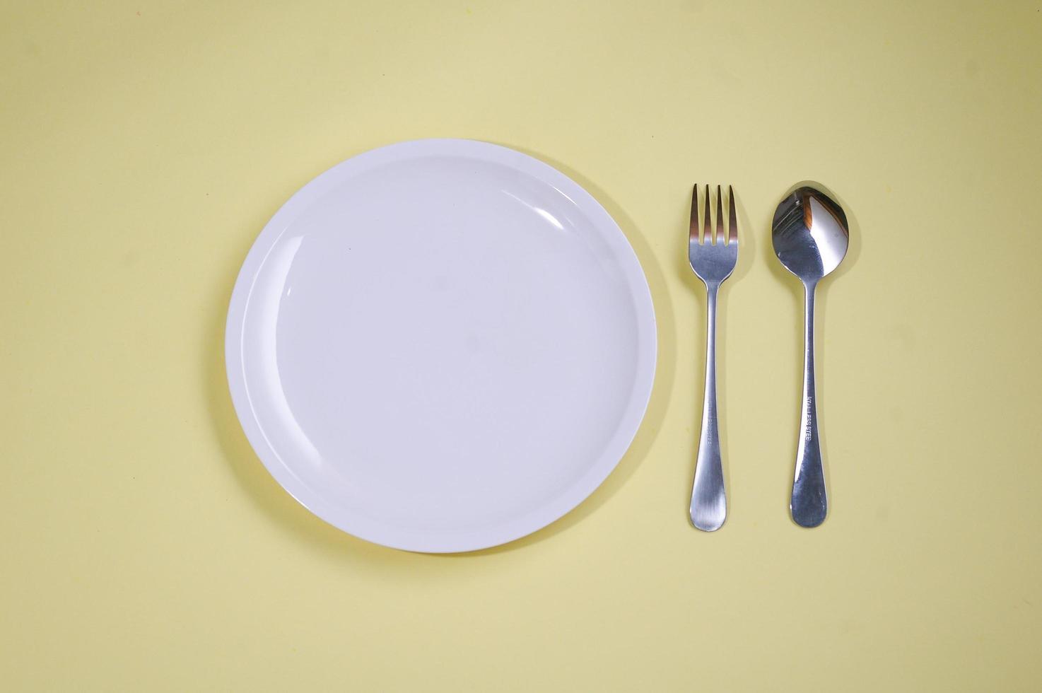 empty plate with spoon yellow background photo