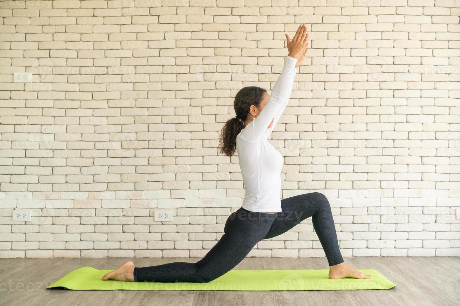 Latin woman practicing yoga on mat photo