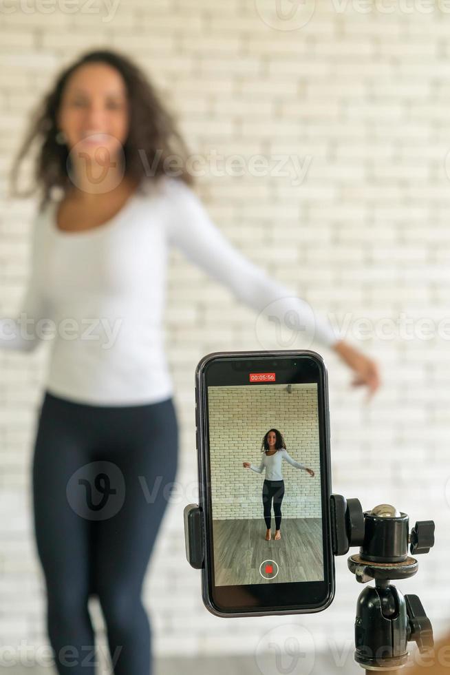 Latin woman created her dancing video by smartphone camera. To share video to social media application. photo