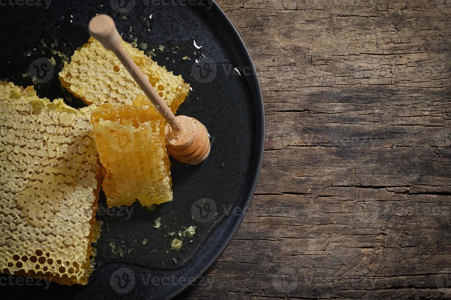 Honeycomb and honey dipper on wooden table photo