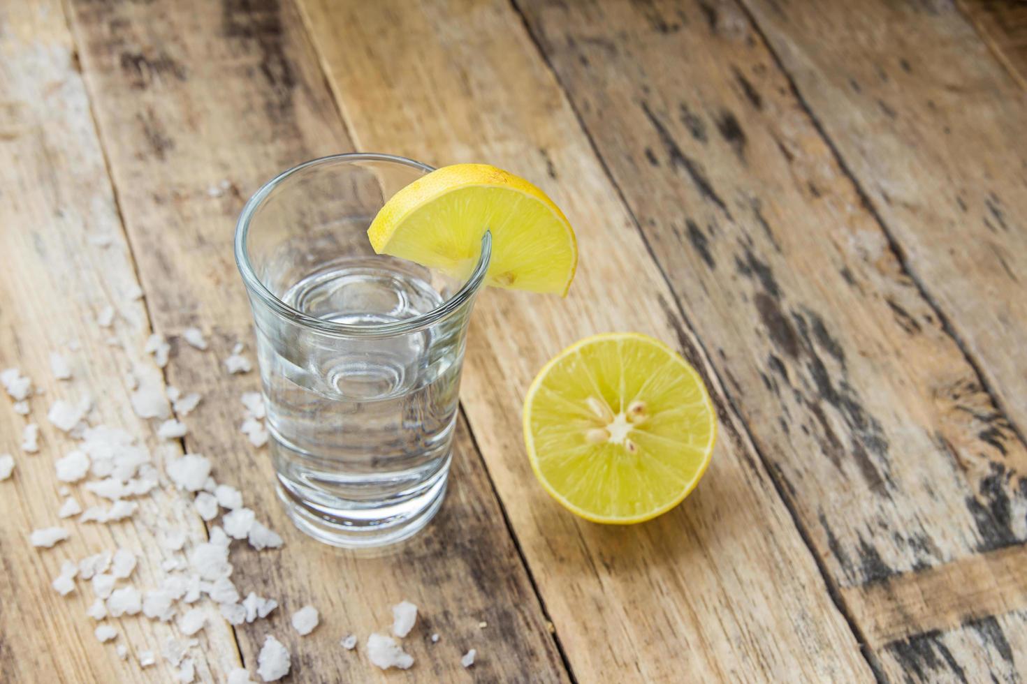 Vodka with lemon on wooden background photo