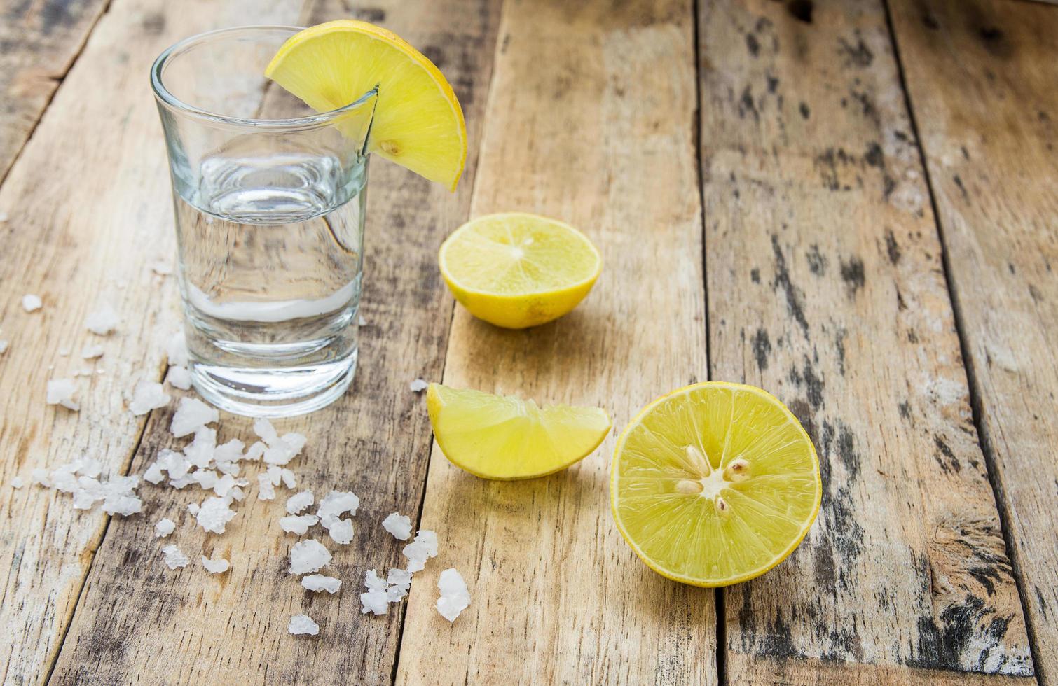 Vodka with lemon on wooden background photo