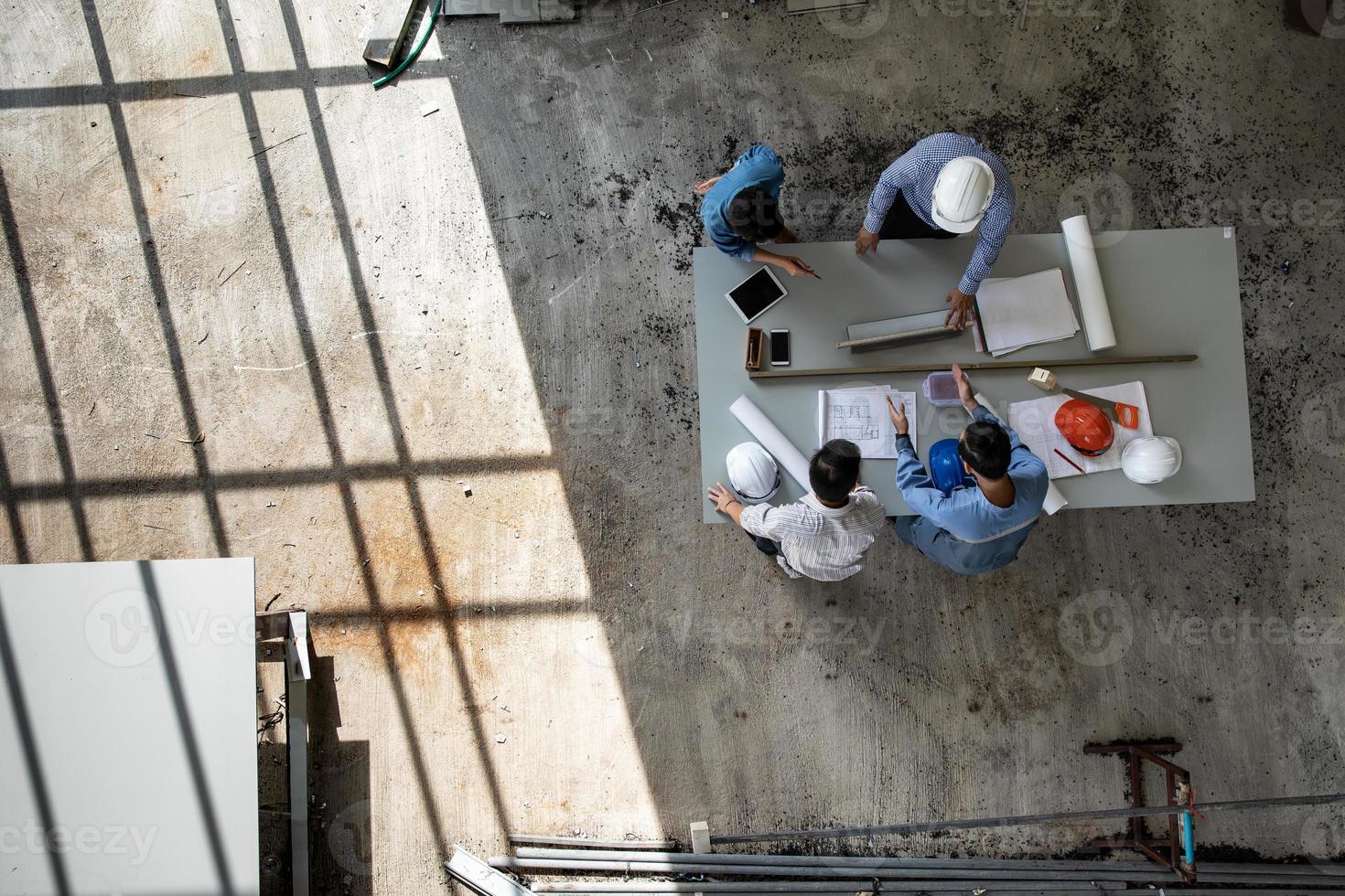 Four persons team of engineers talk together to review constuction material photo